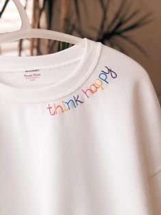 a white t - shirt with the words think yoga embroidered on it