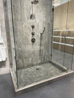 a walk in shower sitting inside of a bathroom next to a towel rack and glass doors