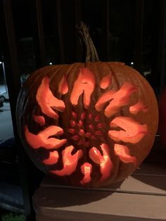 a carved pumpkin sitting on top of a wooden table next to an orange pumpkin with the shape of a flower