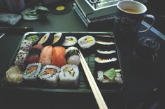 sushi and chopsticks on a black tray