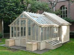 a small wooden greenhouse sitting on top of a lush green field