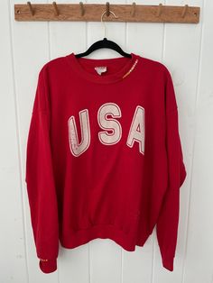 "Vintage 90's USA Crewneck Sweatshirt with hand stitched embroidery on collar and sleeve cuff.  Vintage Gear. Unisex Adult Sizing **Vintage sizing varies, please consult measurements.  Other details: Brand: Santee by Puma Made in: USA Material: Cotton & Polyester Colour: Red Size: XL Style: Crewneck Sweatshirts Pattern: Graphic  **Measurements*  Chest (Pit to pit): 24.5\" Length (Neck to hem): 26\" Sleeve (Pit to cuff): 23\" * All Measurements done on flat laying garments Composition: 50% cotton, 50% polyester. No holes. Bleach stain - see pictures.  Please note, each item is preowned. There is a story/tale behind each stain, hole, pull etc. Perfectly imperfect, however, please consult pictures closely and read all descriptions. All sales FINAL.  Check us out on Instagram for vintage drops Vintage Long Sleeve Tops With Embroidered Logo, Vintage Red Tops With Ribbed Cuffs, Vintage Red Top With Ribbed Cuffs, Vintage Long Sleeve Sweatshirt With Letter Embroidery, Vintage Long Sleeve Tops With Embroidered Text, Vintage Crew Sweatshirt With Embroidery, Vintage Embroidered Crew Sweatshirt, Vintage Relaxed Fit Top With Embroidered Logo, Vintage Cotton Tops With Letter Embroidery