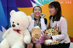 two women sitting next to each other with stuffed animals in front of them and smiling