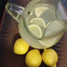 a pitcher filled with lemons sitting on top of a table