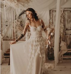 a woman in a white dress standing next to a bed