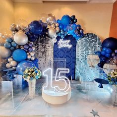 an arrangement of balloons and flowers on display in a room with a sign that reads fifteen