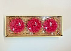 three pink flowers are placed in a gold box on the wall next to each other