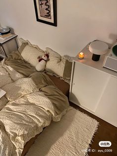 an unmade bed with pillows and blankets on it in front of a white wall