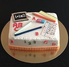 a cake that is shaped like a ruler and some school supplies on top of it