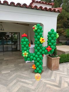 a large balloon cactus sitting in front of a building next to a potted plant