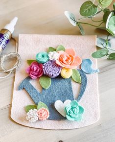 felt flowers are placed on top of a teapot