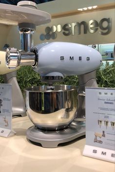 a silver mixer sitting on top of a counter next to a sign that says smeg