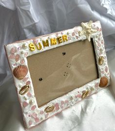 a pink and white photo frame with seashells on it that says summer in gold lettering