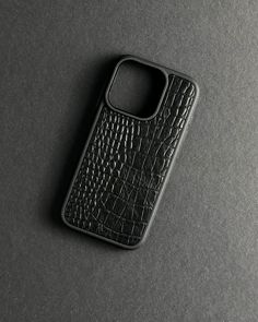 a black cell phone case sitting on top of a table next to a gray wall