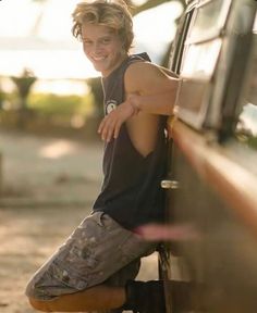 a young man leaning on the side of a car