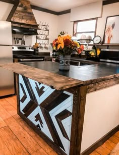 a kitchen with an island made out of wood and painted designs on the counter top