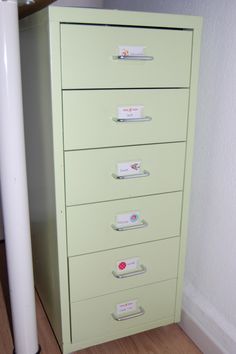 a light green filing cabinet with labels on the drawers