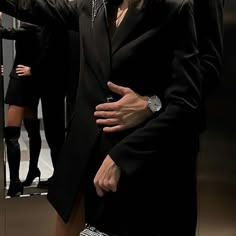 a man in a suit and tie standing next to a mirror with his hands on his hips