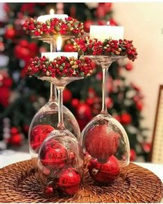 two wine glasses filled with red balls and candles