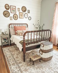 a bed sitting on top of a wooden floor next to a white wall with pictures above it