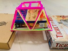 a stack of books sitting on top of a wooden table next to a cardboard box