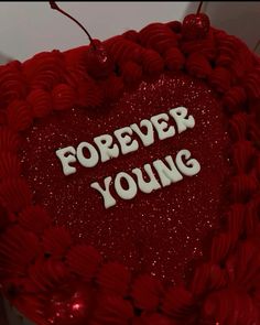 a heart shaped cake with the words ropeyer young on it's side, surrounded by red and white icing