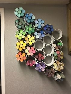 there are many different colored crayons in the cup holders on this wall hanging