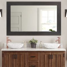 a bathroom vanity with two sinks and a large mirror over the sink that hangs above it