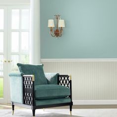 a living room with blue walls and white trim on the walls, two chairs in front of a chandelier