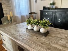 three white vases are sitting on a wooden table in front of a television set