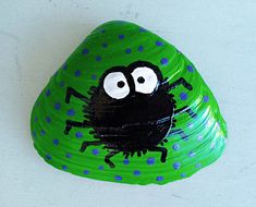 a green paper plate with a black spider painted on it's face and eyes