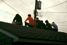 five men sitting on the roof of a house