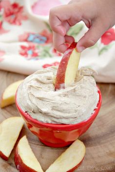 a person dipping an apple into a fruit dip