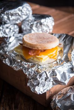 a bacon and egg sandwich sitting on top of aluminum foil