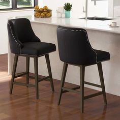 two black bar stools sitting in front of a counter