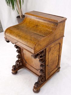 an old wooden desk sitting next to a potted plant