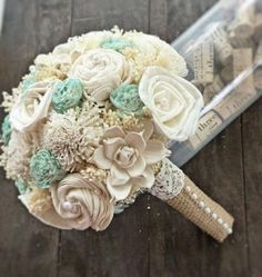 a bridal bouquet with white and green flowers on a wooden table next to a ruler