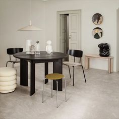 a dining room with pink walls and black table in the center, chairs around it