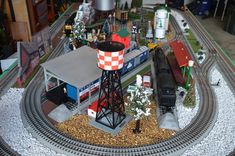 a model train set on top of a table next to a building and water tower