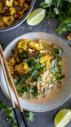 two bowls filled with food next to chopsticks and cilantro on a table