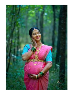 a woman in a pink sari posing for the camera with her hand on her hip