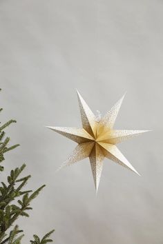 a gold and white ornament hanging from a tree