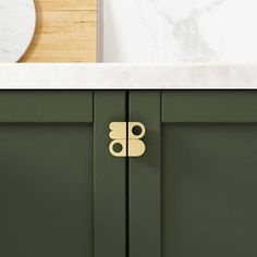 a close up of a green cabinet with a white counter top and a mirror in the background