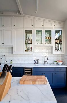 a kitchen with marble counter tops and blue cabinets, along with white subway backsplashes