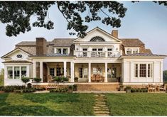 a large white house sitting on top of a lush green field