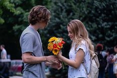 a man handing flowers to a woman on the street