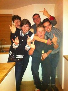 a group of young men standing next to each other in a kitchen with their hands up