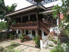 the house is surrounded by trees and greenery on both sides of the porches