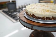 a cake sitting on top of a wooden table next to a metal pan filled with frosting