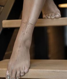 a woman's foot with a small spider tattoo on her left leg, sitting on a wooden step